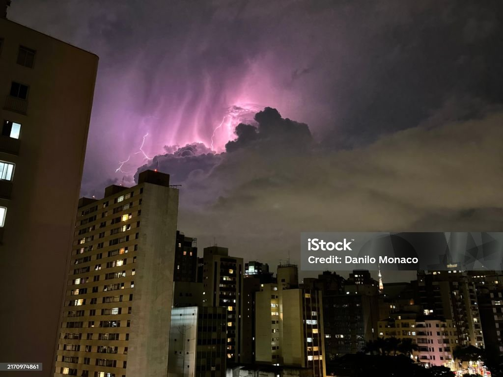Céu noturno de cidade com nuvens e raios